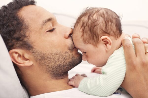 father-holds-infant-kissing-his-forehead